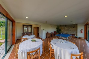 Un comedor con mesas redondas, una mesa de billar y una pared de piedra.