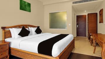 A hotel room with a large bed, a wooden nightstand, a desk, and a chair.