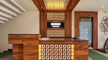 A reception desk with a geometric patterned back panel, a sign reading 'PALETTE YO-Serviced', and a modern art piece on the wall.