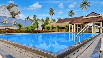 Una piscina con superficie de agua azul cristalina, rodeada de vegetación tropical y palmeras.