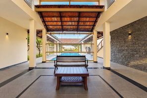 A poolside area with a wooden bench, clear glass walls, and a stone wall. - Palette Sealine Beach Resort,  (Kochi)