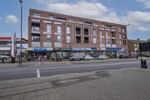 Ein mehrstöckiges Gebäude mit verschiedenen Geschäften im Erdgeschoss, darunter ein Tesco Express und Papa John's.