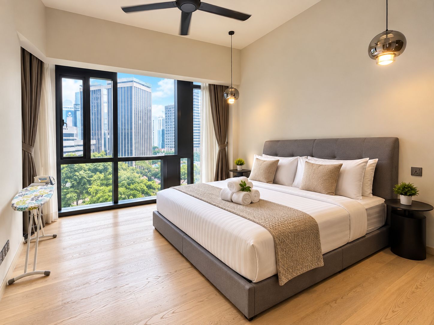 A modern bedroom with a large bed, a standing fan, a small table with a plant, and a view of the city through large windows.