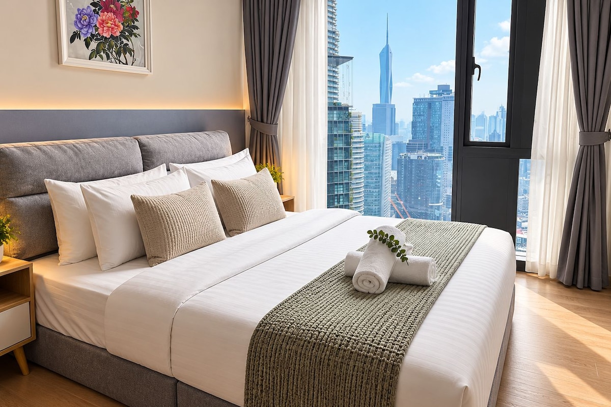 A modern hotel room with a large bed, a view of the city skyline, and a cityscape visible through the window.