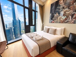 A hotel room with a large bed, a city view, a black leather chair, and a painting on the wall. - Star Residences KLCC -Royale Stay  (Kuala Lumpur)