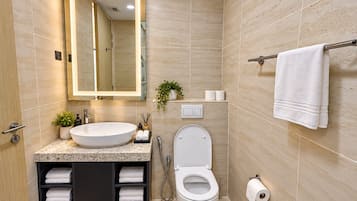 Un baño moderno con un lavamanos grande, inodoro y perchero para toallas.