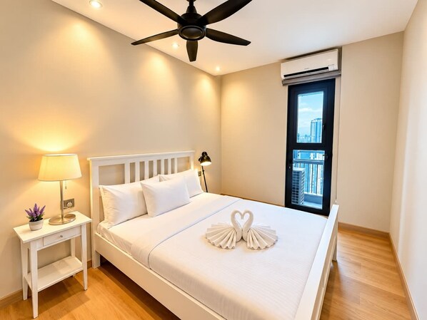 A hotel room with a bed, bedside table, lamp, and a view of the city through a window. - Star Residences KLCC -Royale Stay (Kuala Lumpur)