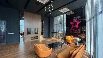 Un área de estar moderna con un televisor grande, asientos cómodos y un letrero visible de 'STAR RESIDENCES'.
