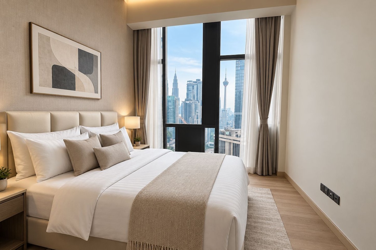 A hotel room with a large bed, a nightstand, a lamp, a window with curtains, and a city view.