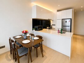 A modern kitchen with white cabinetry, a central island, and a dining table with chairs.