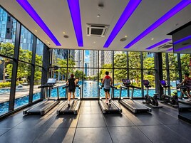 Un gimnasio con cintas de correr y equipo de ejercicio, ventanas amplias y vista a una piscina.