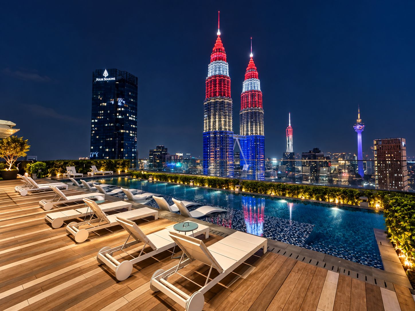 A rooftop pool area with lounge chairs and a city skyline in the background.