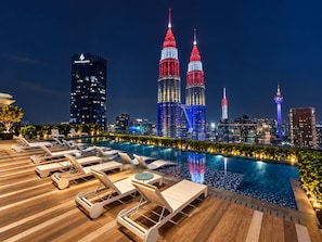 A rooftop pool area with lounge chairs and a city skyline in the background. - Star Residences KLCC -Royale Stay  (Kuala Lumpur)