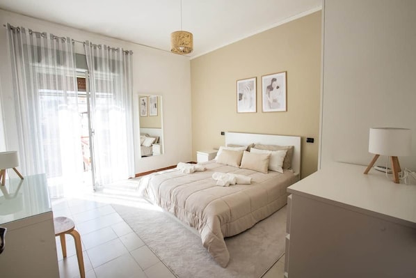Une chambre à coucher avec un lit, des tables de chevet, un bureau et une chaise.
