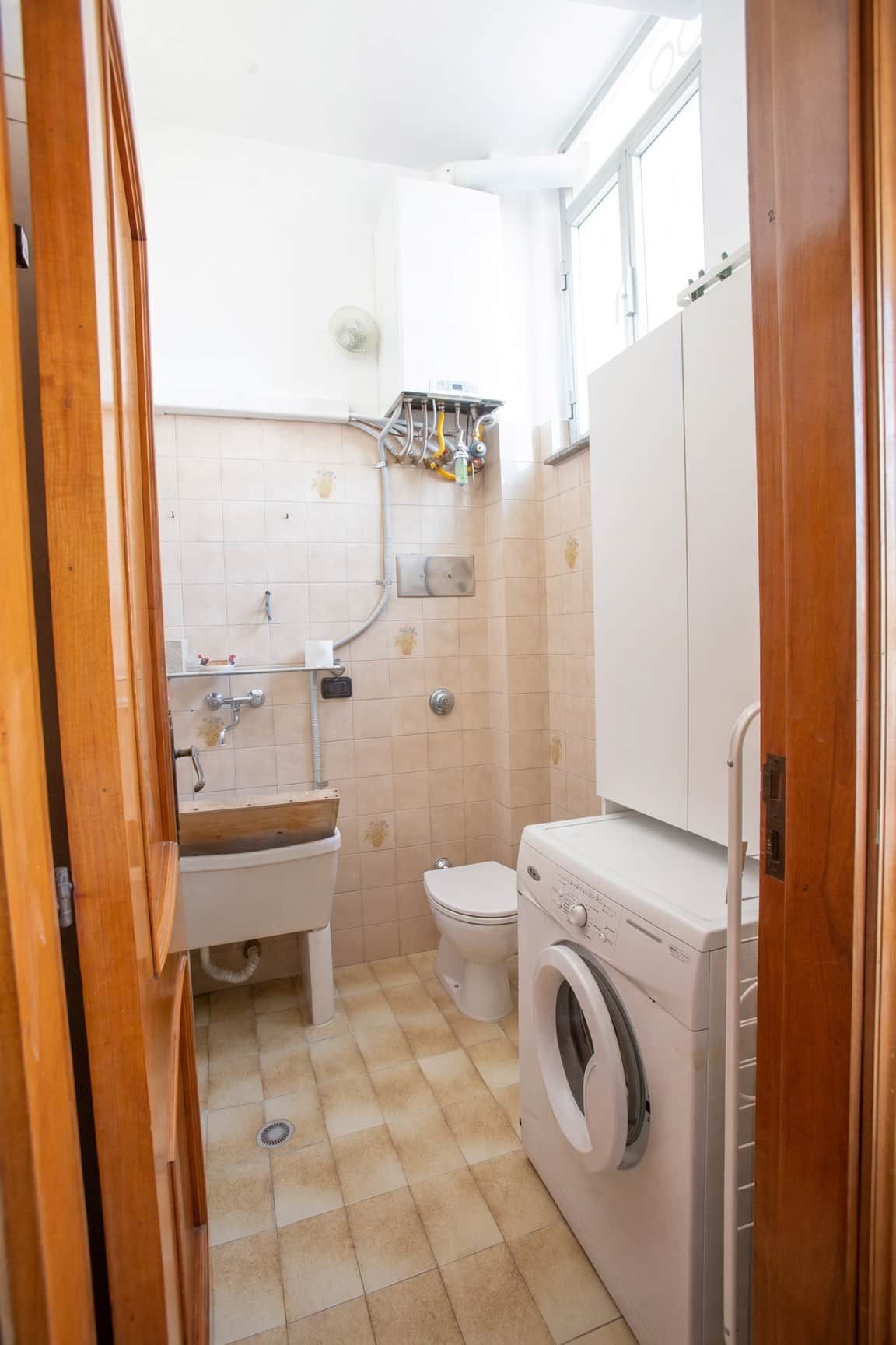 Pieni kylpyhuone, jossa on pesuallas, wc ja pesukone.