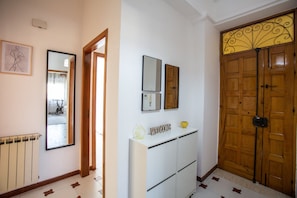 A hallway with a radiator, a white console table with a welcome sign, and a wooden door with a decorative panel.