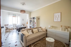 Un salon comprenant un canapé, une table basse, une bibliothèque et un coin repas avec une table et des chaises.