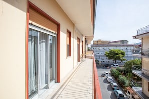 A balcony with a view of parked cars and buildings in the background.