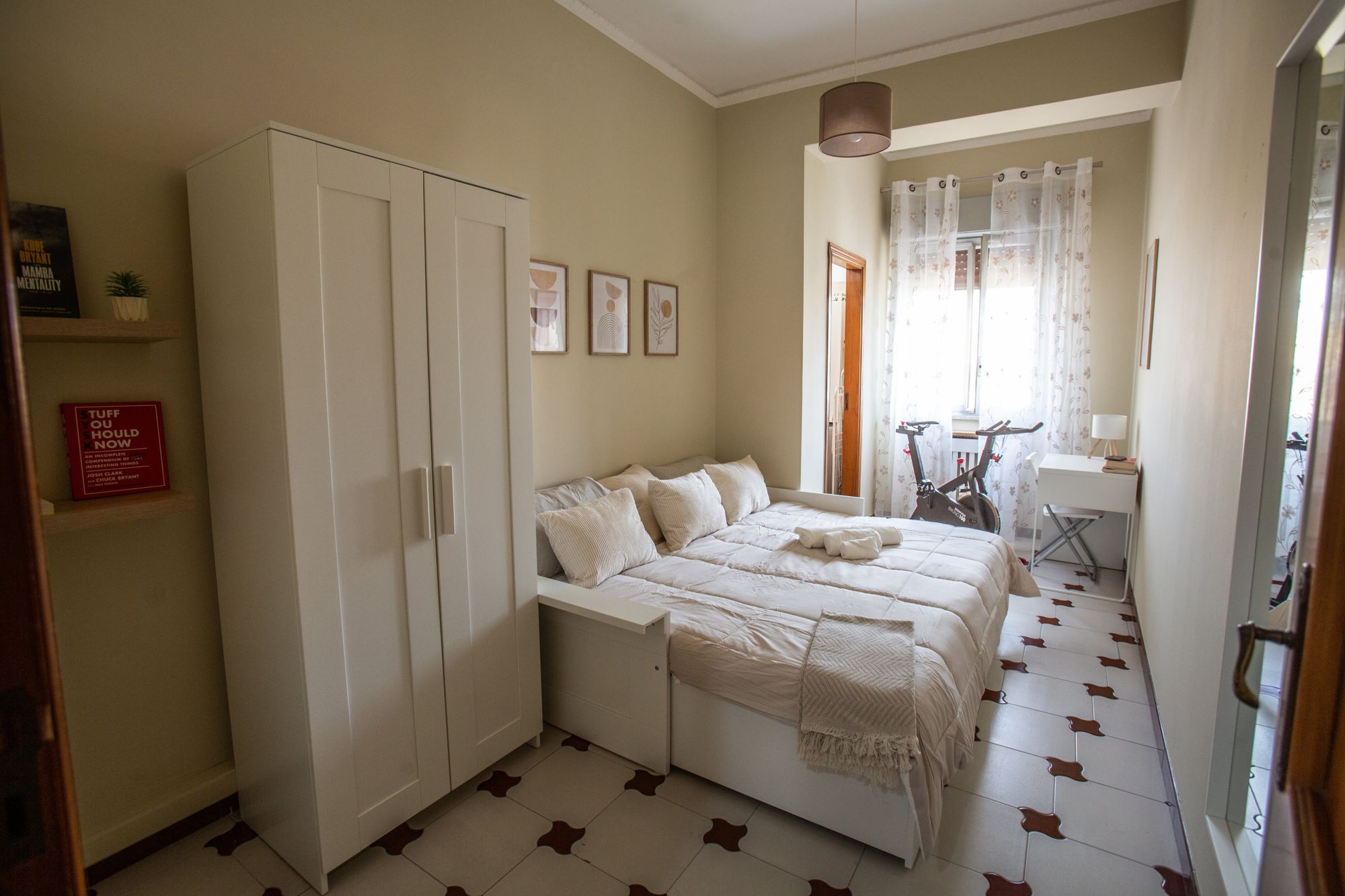 Een slaapkamer met een bed, kast en een bureau met stoel.