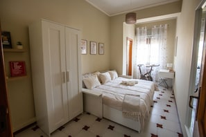 A bedroom with a bed, wardrobe, and a desk with a chair.
