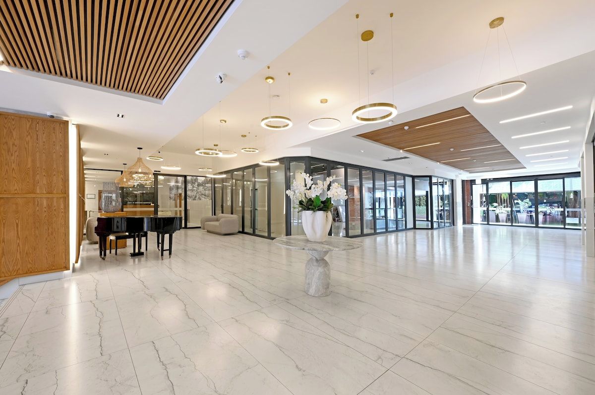 A spacious lobby with a piano, seating area, and a central decorative table.