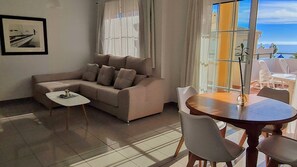 A living room with a sofa, a small table, and a dining area with chairs. - Burriana Beach Apartment (Nerja)