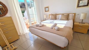 Une chambre d’hôtel avec un lit, une table de chevet, une commode et une vue sur l’extérieur.