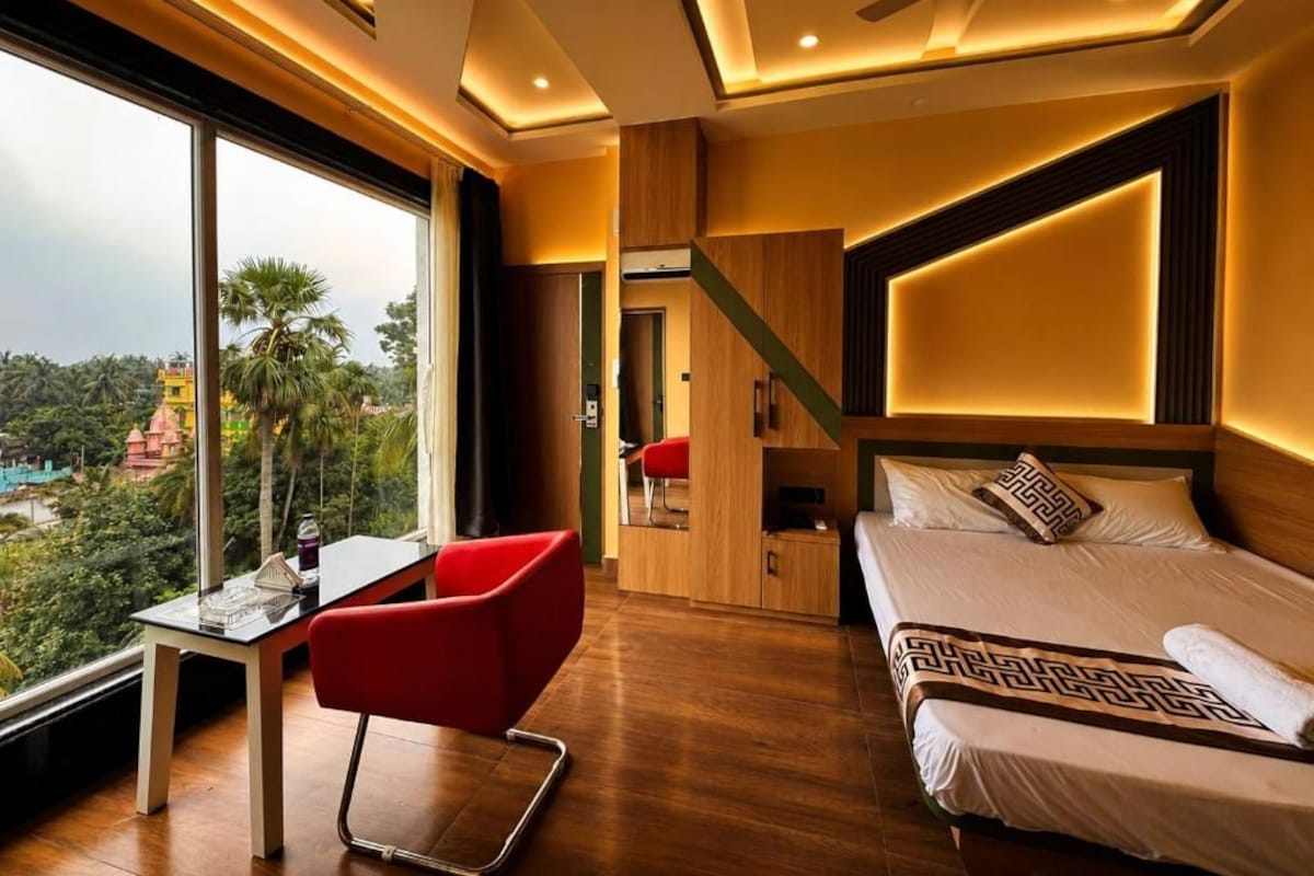 Ein Hotelzimmer mit Bett, Schreibtisch und Stuhl. Ein großes Fenster bietet einen Blick nach draußen.