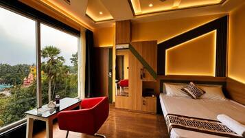 Quarto de hotel com uma cama, uma escrivaninha e uma cadeira. Uma janela grande oferece vista para o exterior.