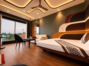 Ein modernes Hotelzimmer mit einem großen Bett, einem Schreibtisch, einem Sessel und Blick auf die Stadt.