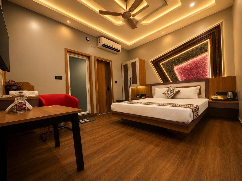 Quarto de hotel moderno com cama, mesas de cabeceira, escrivaninha, cadeira e ventoinha no teto.
