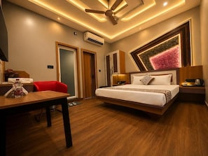 Ein modernes Hotelzimmer mit Bett, Nachttischen, Schreibtisch, Stuhl und Deckenventilator.
