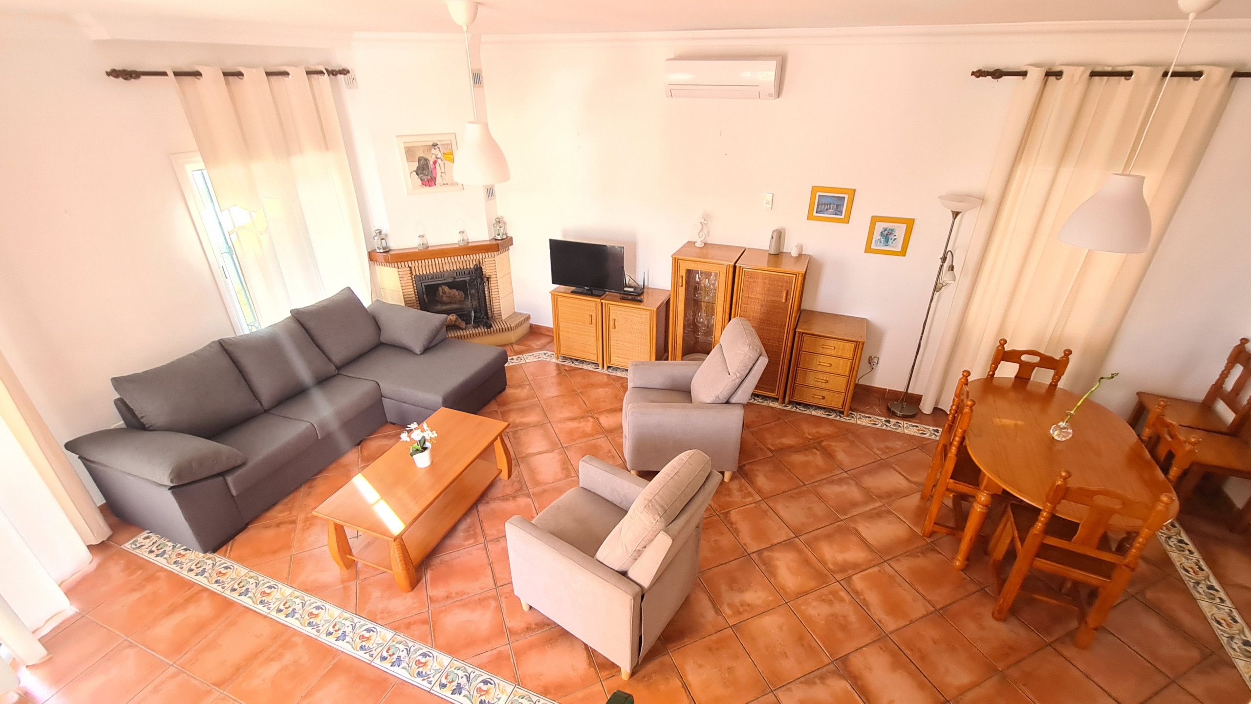Una sala de estar con sofá, sillones, una mesa de centro, televisor y chimenea.