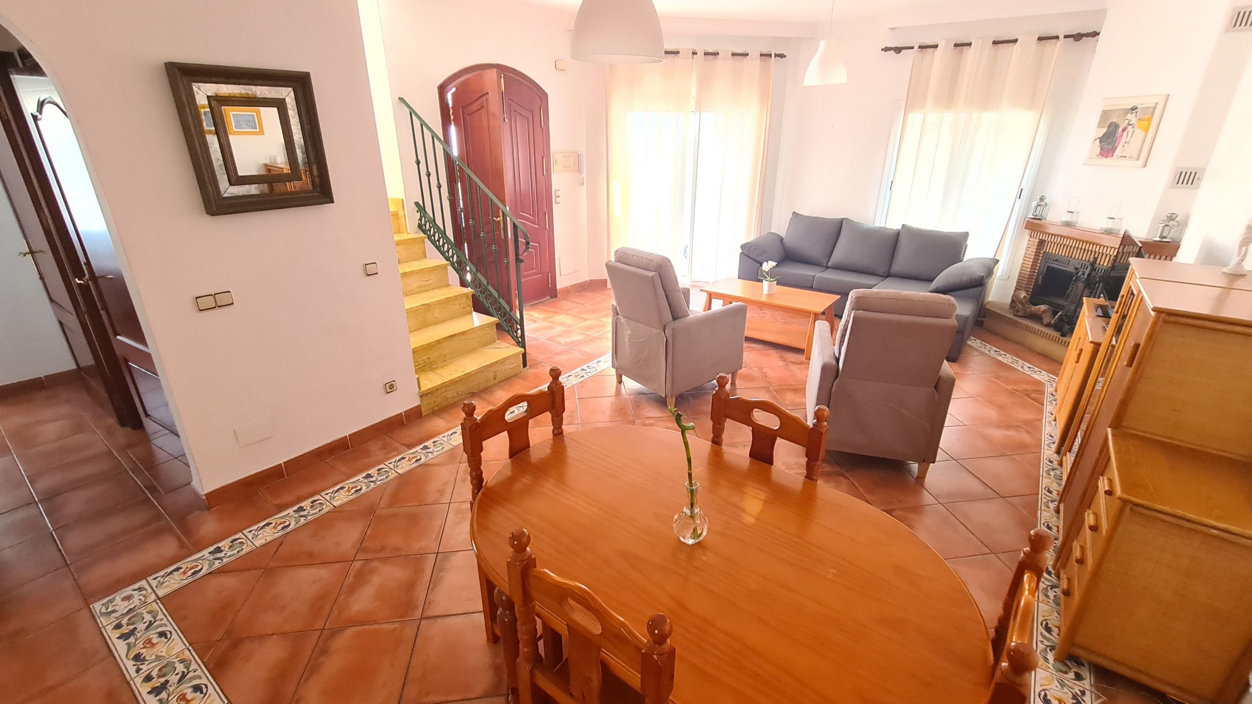 Un vaste espace de vie comprenant une table à manger, des canapés et un escalier.