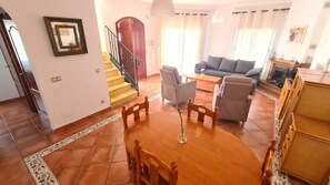 Ein geräumiger Wohnbereich mit Esstisch, Sofas und einer Treppe.