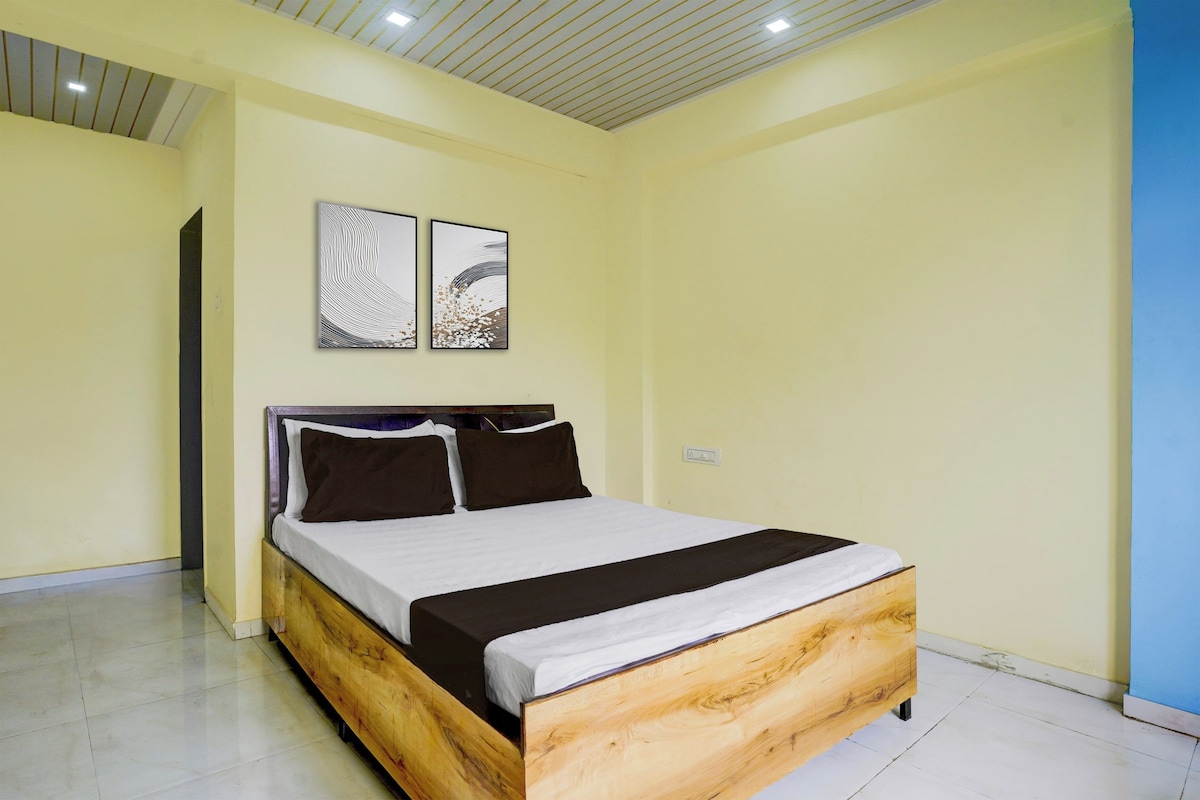 A bedroom with a wooden bed, white bedding, and two abstract paintings on the wall.