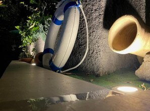 A concrete wall with a rope and a white object, possibly a lifebuoy, leaning against it. - Il Giardino dell'Etna (Mascalucia)