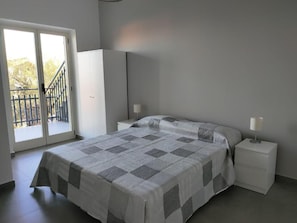 A bedroom with a bed, nightstands, a wardrobe, and a balcony. - Il Giardino dell'Etna (Mascalucia)