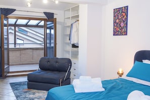 A bedroom with a bed, a sofa, a wardrobe, and a view of a building through a glass door. - CasaNova • Jacuzzi • 9 guests • 4 bedrooms (Zona Industriale)