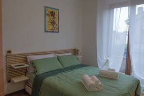 A bedroom with a bed, pillows, a bedside table, a nightstand, a painting on the wall, and a window with curtains. - CasaNova • Jacuzzi • 9 guests • 4 bedrooms (Zona Industriale)