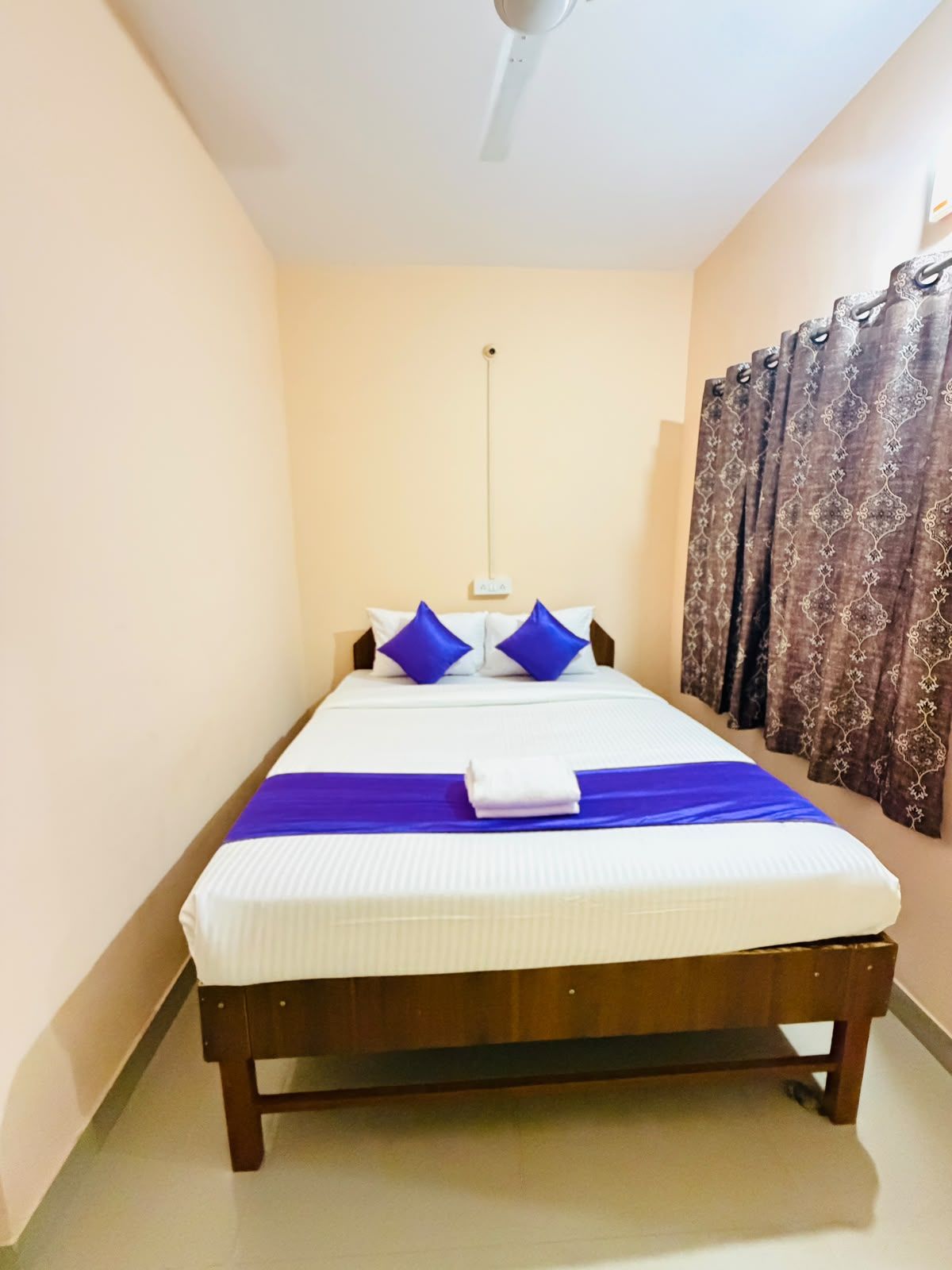 A single bed with a wooden frame, white bedding, and blue accents.