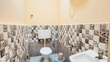 Un baño con inodoro, lavamanos y calentador de agua instalado en la pared.