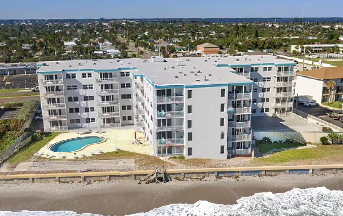 Ett hotell med flera våningar, en pool på taket och utsikt över stranden.