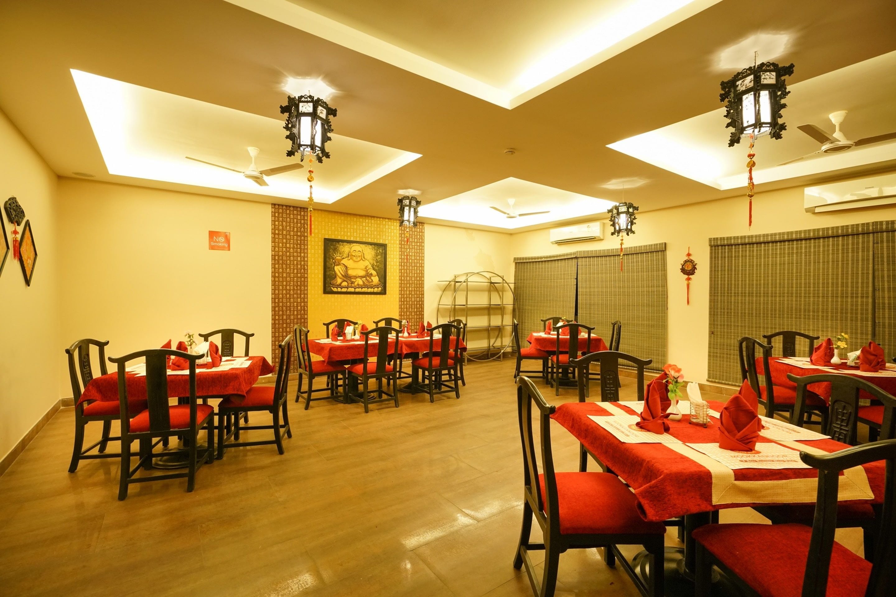 A dining area with multiple tables and chairs, ceiling fans, and traditional wall decorations.