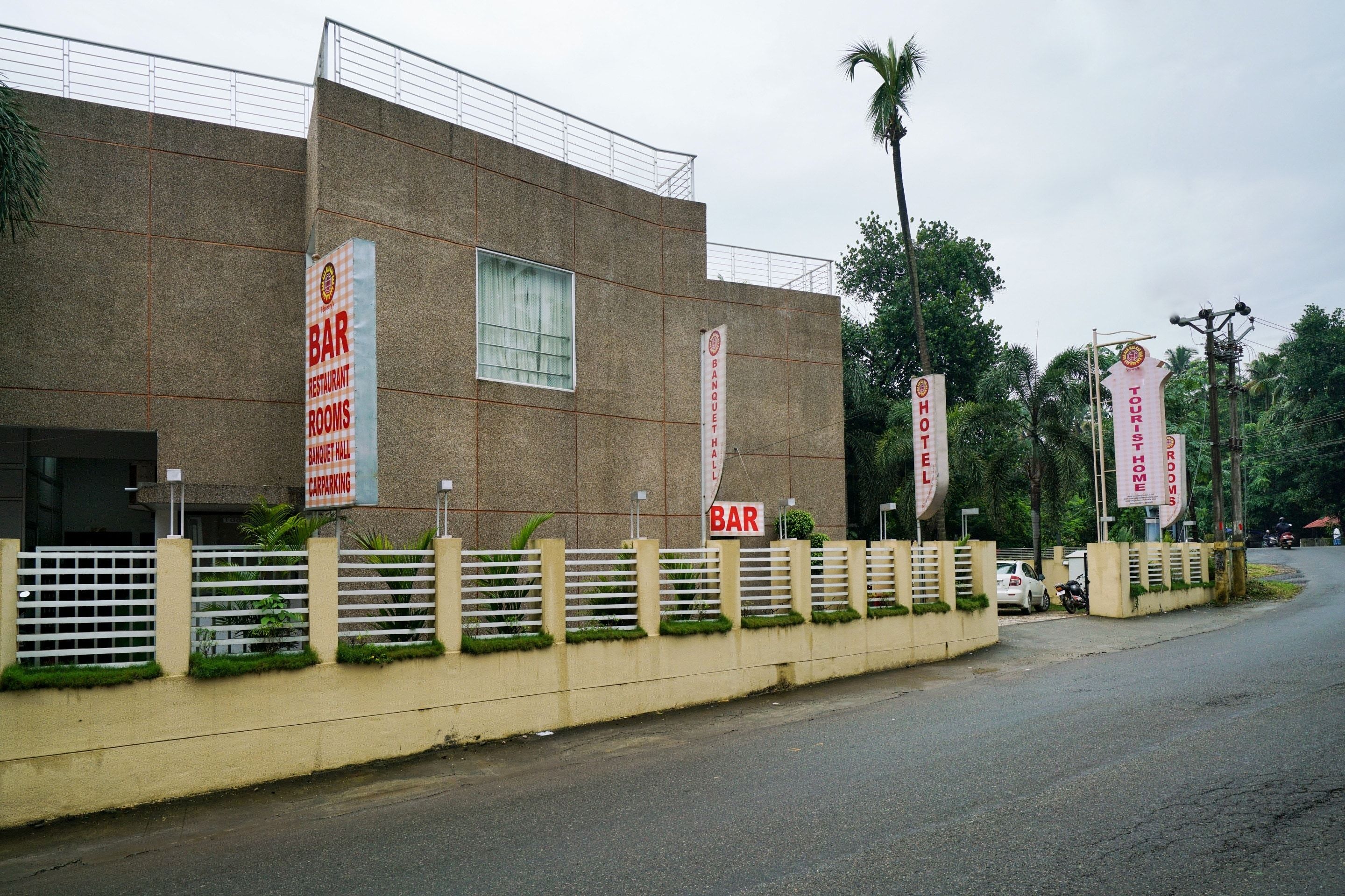 A building with multiple signs indicating the presence of a bar, banquet hall, car parking, and tourist home rooms.