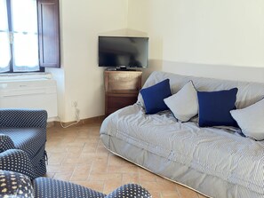 A living room with a sofa, a television, and a patterned rug. - Camigliano Wine State - Ghiandaie (Camigliano)
