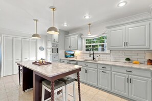 A modern kitchen with white cabinetry, a marble countertop, and pendant lighting. - Pondside Home | Hot Tub • Fire Pit • Beach Access (Greenwood Lake)