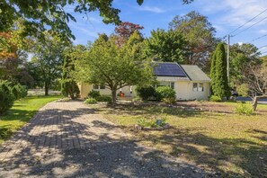 Een woonhuis met een verharde oprit, een dak voorzien van zonnepanelen en een keurig onderhouden tuin.