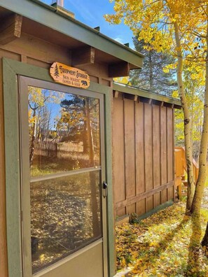 A wooden shed with a sign indicating it is a storage area for equipment, skis, boards, games, and gear. - Sundance Festival Cabin – 30 Min to Boulder! Peaceful meadow• 4 BR• Ski Eldora  (Golden)