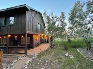 Una cabana de fusta amb un porxo, seients a l'aire lliure i llums de garlandes.